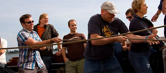 Enkele leden hard aan het werk om de zeilen te heisen.